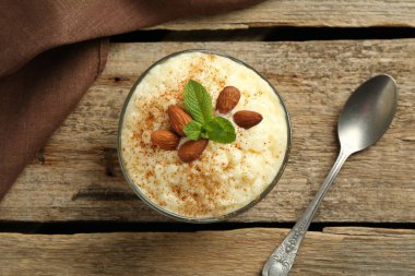 Tarçınlı lezzetli sütlaç, badem ve nane şekeri ahşap masada servis edilir.