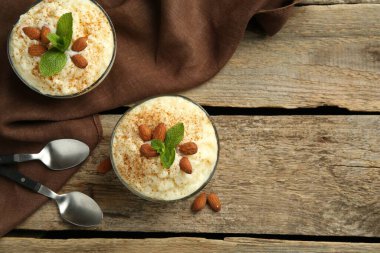 Tarçınlı lezzetli sütlaç, badem ve nane şekeri ahşap masada servis edilir. Metin için boşluk