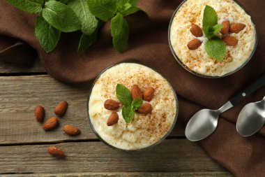 Tarçınlı lezzetli sütlaç, badem ve nane şekeri ahşap masada servis edilir.