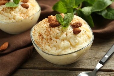 Tarçınlı lezzetli sütlaç, badem ve nane, ahşap masada servis edilir, yakın plan.