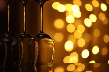 Bulanık ışıklara karşı cam ayna yüzeyinde birçok temiz bardak, yakın plan. Bokeh etkisi