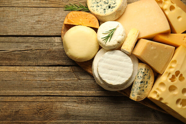 Different types of cheese on wooden table, top view. Space for text