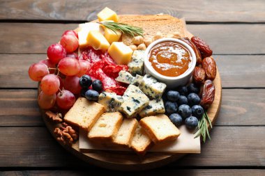 Tahta masadaki farklı lezzetli peynir ve diğer atıştırmalıklar, yakın plan.
