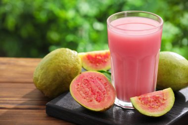 Guava suyunu tazeliyorum ve ahşap masada taze meyveler, yakın plan.
