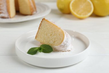 Lezzetli limonlu kek, pudra şekerli ve nane şekerli, beyaz ahşap masa, yakın plan.