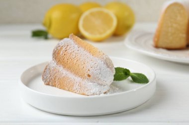 Lezzetli limonlu kek, pudra şekerli ve nane şekerli, beyaz ahşap masa, yakın plan.