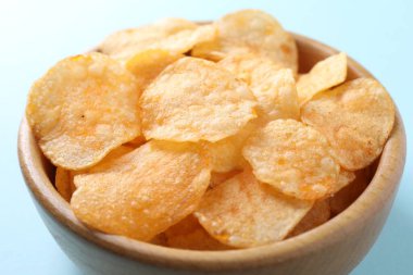 Açık mavi arka planda, kasede patates cipsi, yakın plan.