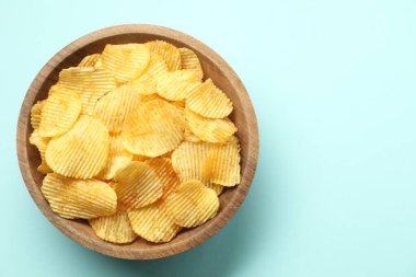 Açık mavi arka planda, kasede leziz patates cipsi, üst manzara. Metin için boşluk