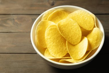 Tahta masadaki kasede patates cipsi, yakın plan. Metin için boşluk