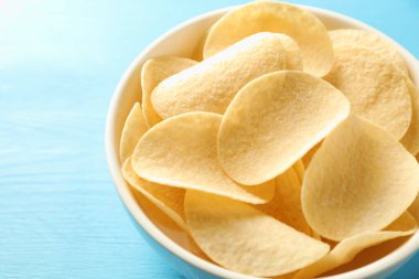 Açık mavi ahşap masada patates cipsi, yakın plan.