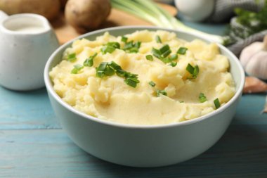 Açık mavi ahşap masada yeşil soğanlı lezzetli patates püresi, yakın plan.