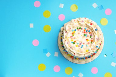 Renkli süslemeli nefis bento keki ve açık mavi masada konfeti, düz konfeti. Metin için boşluk