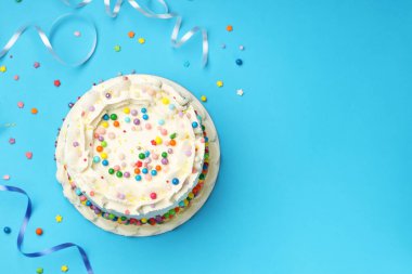 Rengarenk serpiştirilmiş nefis bento keki ve açık mavi masada serebentin şeritler, düz uzanma. Metin için boşluk