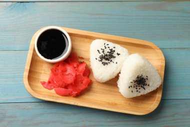 Pirinç topları (onigiri), soya sosu ve açık mavi ahşap masa üzerinde turşulu zencefil, üst manzara. Geleneksel Japon yemeği