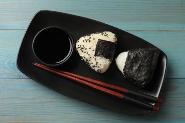 Pirinç topları (onigiri) açık mavi ahşap masa üzerinde servis edilir. Geleneksel Japon yemeği