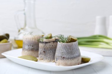 Turşulu ve dereotlu lezzetli ringa dürümleri hafif fayanslı masada, yakın plan.