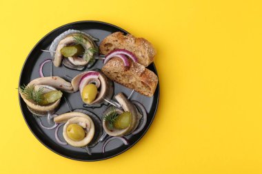 Sarı masada zeytinli, turşulu, dereotlu, soğanlı ve ekmek parçalı lezzetli ringa dürümleri. Metin için boşluk