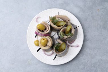 Gri desenli masada zeytinli, turşulu, dereotlu ve soğanlı lezzetli ringa dürümleri.