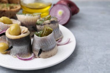 Gri masada zeytinli, turşulu, dereotlu ve soğanlı lezzetli ringa dürümleri.