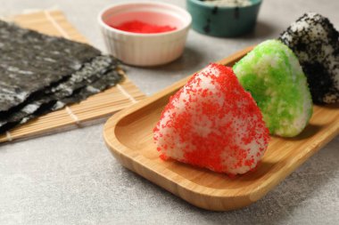 Lezzetli tobiko onigiri (Japon pirinç topları) gri masada servis edilir, yakın plan.
