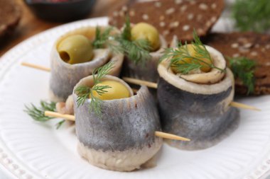 Zeytinli lezzetli ringa dürümleri, tabakta dereotu ve ekmek, yakın plan.