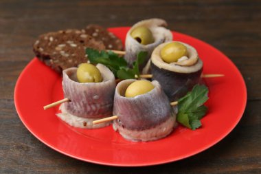 Lezzetli ringa dürümleri zeytin, maydanoz ve ekmek ahşap masada, yakın plan.