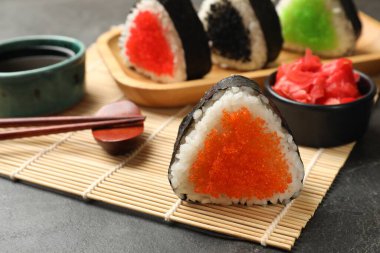 Lezzetli tobiko onigiri (Japon pirinç topları) siyah masada servis edilir.
