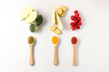 Bebek maması. Kaşıklar içinde lezzetli püre ve beyaz arka planda farklı malzemeler.