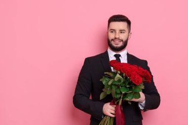 Pembe arka planda kırmızı gül buketi olan mutlu adam, mesaj için yer.