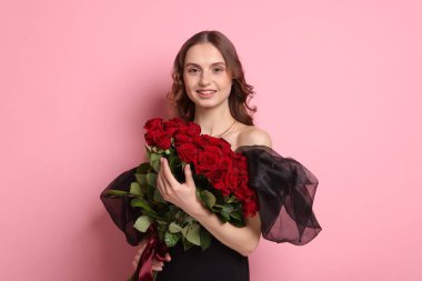 Gülen kadın pembe arka planda bir buket gülle