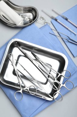 Açık gri zemin üzerinde farklı cerrahi araçlar, düz yatıyordu