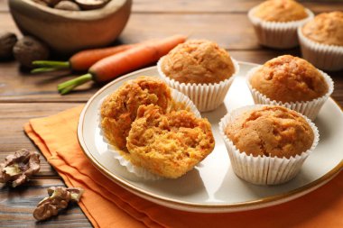 Lezzetli havuçlu kekler, taze sebzeler ve ahşap masada cevizler, yakın plan.