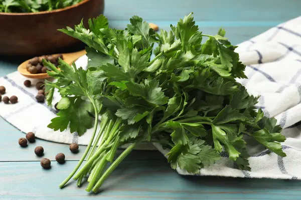 Açık mavi ahşap masada taze maydanoz ve biber, yakın plan.