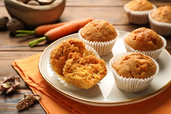 Lezzetli havuçlu kekler, taze sebzeler ve ahşap masada cevizler, yakın plan.