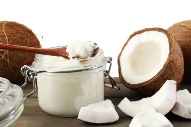 Hindistan cevizleri, pişirme yağı ve kaşık ahşap masada beyaz arka planda