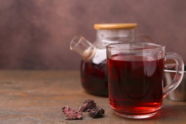 Cam bardakta leziz amberçiçeği çayı, çaydanlık ve ahşap masada kuru roselle sepals, yakın plan. Metin için boşluk