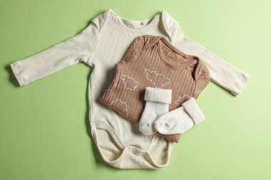 Açık yeşil arka planda bebek kıyafetleri, düz yatış