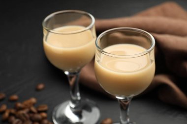 Bardakta kremalı kahve likörü ve siyah masada fasulye, yakın plan.