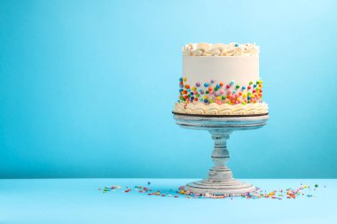 Açık mavi masaya renkli şekerlemeler serpiştirilmiş nefis bento keki, metin için yer.