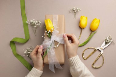 Çiçek kutusu, çiçek, makas ve bej arka planda kurdele olan bir çiçekçi.