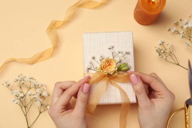 Çiçek kutusu, çiçek, makas ve bej arka planda kurdele olan bir çiçekçi.