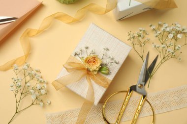 Çiçekçi. Bej arka planda kutular, çiçekler, kurdele ve makas, düz uzanma