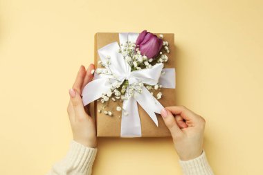 Çiçekçi hediye kutusu ve çiçekli bej arka plan, üst manzara