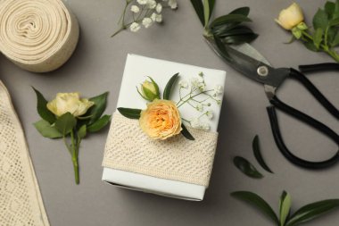 Çiçekçi. Kutu, çiçekler, yapraklar ve makas gri arka planda, düz yatar