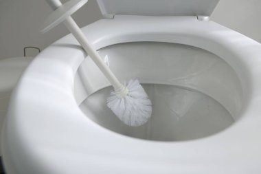 Cleaning toilet bowl with brush indoors, closeup