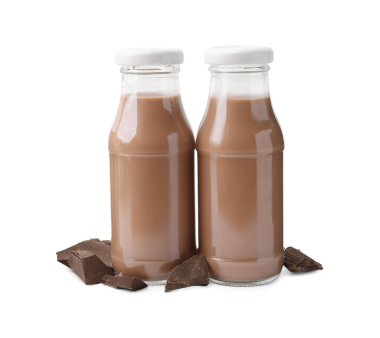 Cam şişelerdeki lezzetli çikolatalı süt ve beyaza izole edilmiş çikolata parçaları.