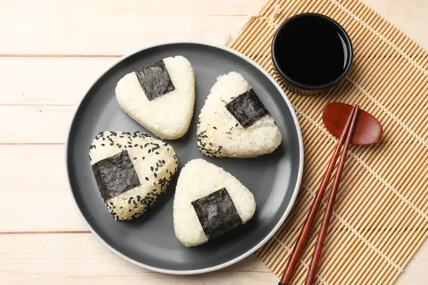Pirinç topları (onigiri), soya sosu ve ahşap masa üzerindeki çubuklar, düz yatak. Geleneksel Japon yemeği