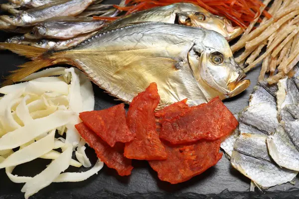 Siyah masada birçok farklı kurutulmuş balık atıştırmalıkları, yakın plan.