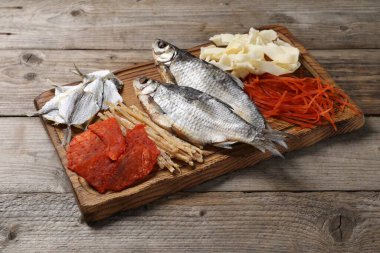 Tahta masada birçok farklı kurutulmuş balık atıştırmalıkları var.