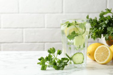 Maydanozlu sağlıklı içecek, salatalık ve limonlu beyaz mermer masa, metin için yer